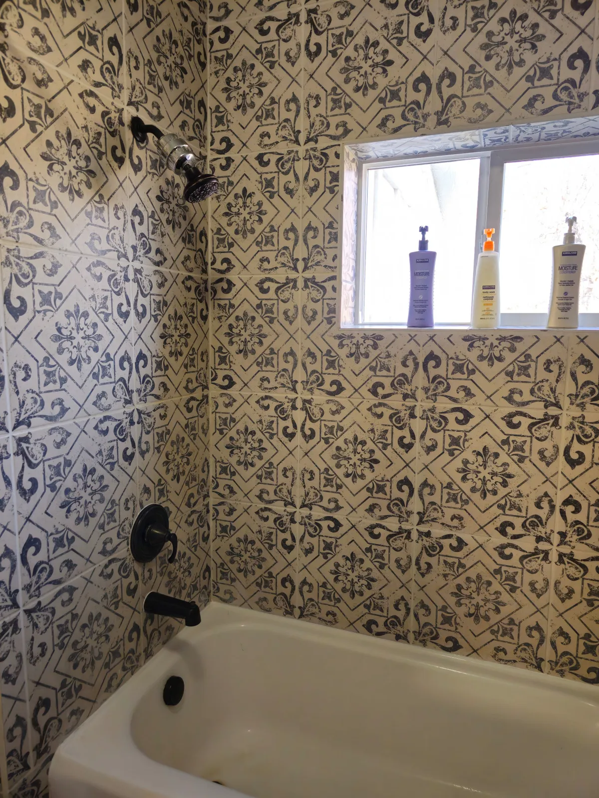A bathroom oasis featuring a stylish bathtub with decorative tile accents, a bright window letting in natural light, and a modern shower fixture. The ambiance is serene and spa-like, perfect for a relaxing soak after a day of adventure.