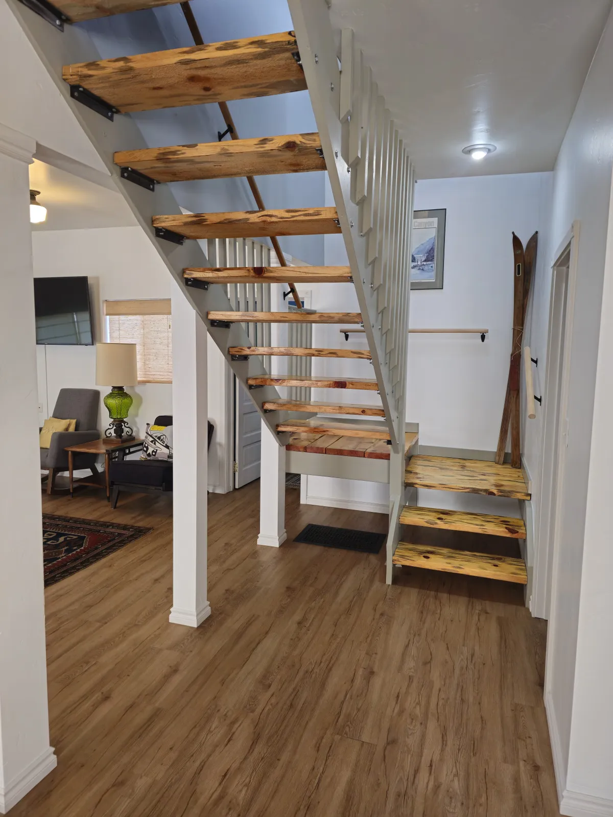 A welcoming seating area at the base of an interior staircase, decorated with ski equipment and wall art. The space feels warm and lived-in, making the transition from outdoor adventure to cozy indoor relaxation seamless.