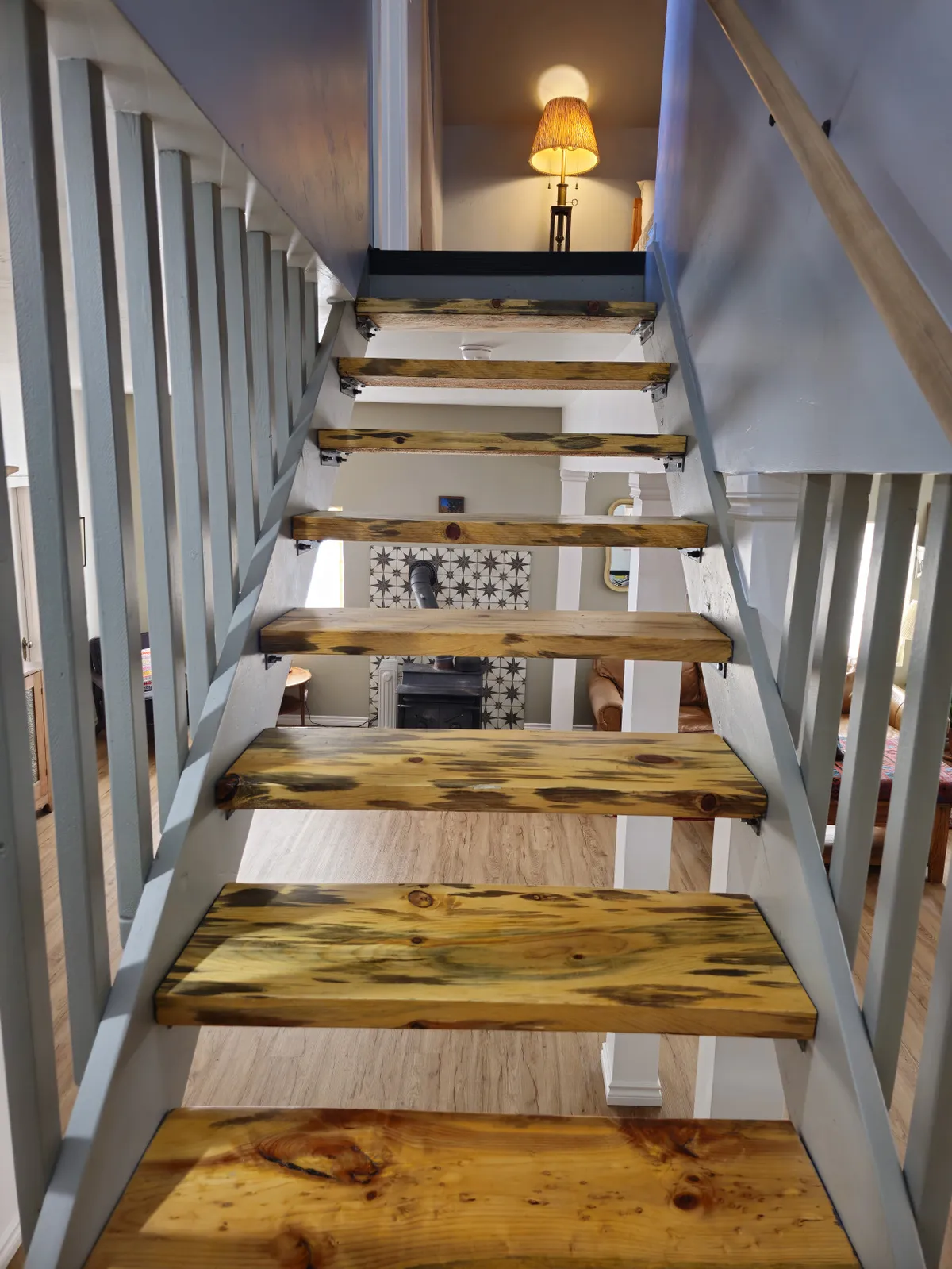 A wooden staircase with a charming railing leads to a comfortable landing, illuminated by warm lighting and decorated with decorative tiles and a lampshade. The scene suggests a welcoming transition between spaces within the home.