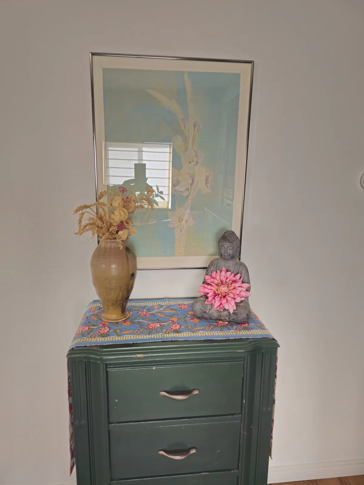 A tranquil vignette highlighting a Buddha statue, delicate floral arrangement, and framed artwork, creating a calm and reflective ambiance. The decor emphasizes serenity and thoughtful design.